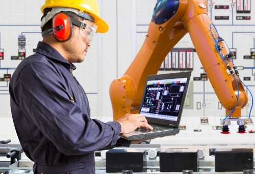 Industrial automation engineer performing PLC diagnostics and remote support on robotic system
